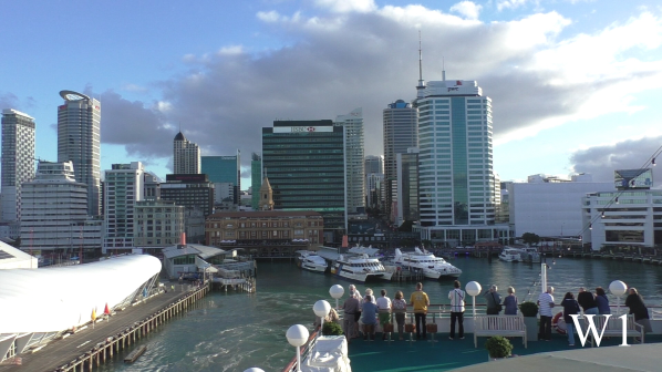 Begeisterte Gäste auf dem Pooldeck von MS Albatros mit Blick auf die Skyline von Auckland