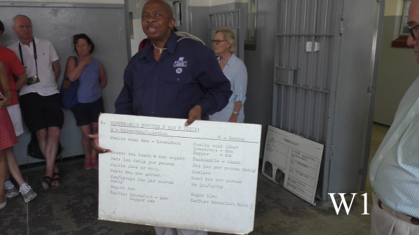 Afrikanischer Führer mit Schautafel in einer Gefängniszelle auf Robben Island