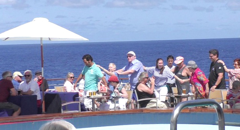 Fröhliche Menschen mit Polonaise auf dem Pooldeck von MS Albatros in der Südsee
